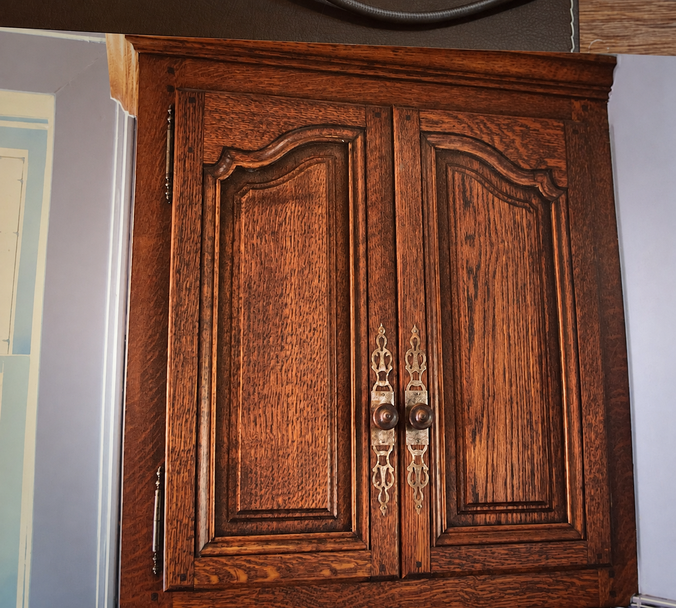 A close-up of the paired custom cabinet doors, carved profiles and decorative hardware.