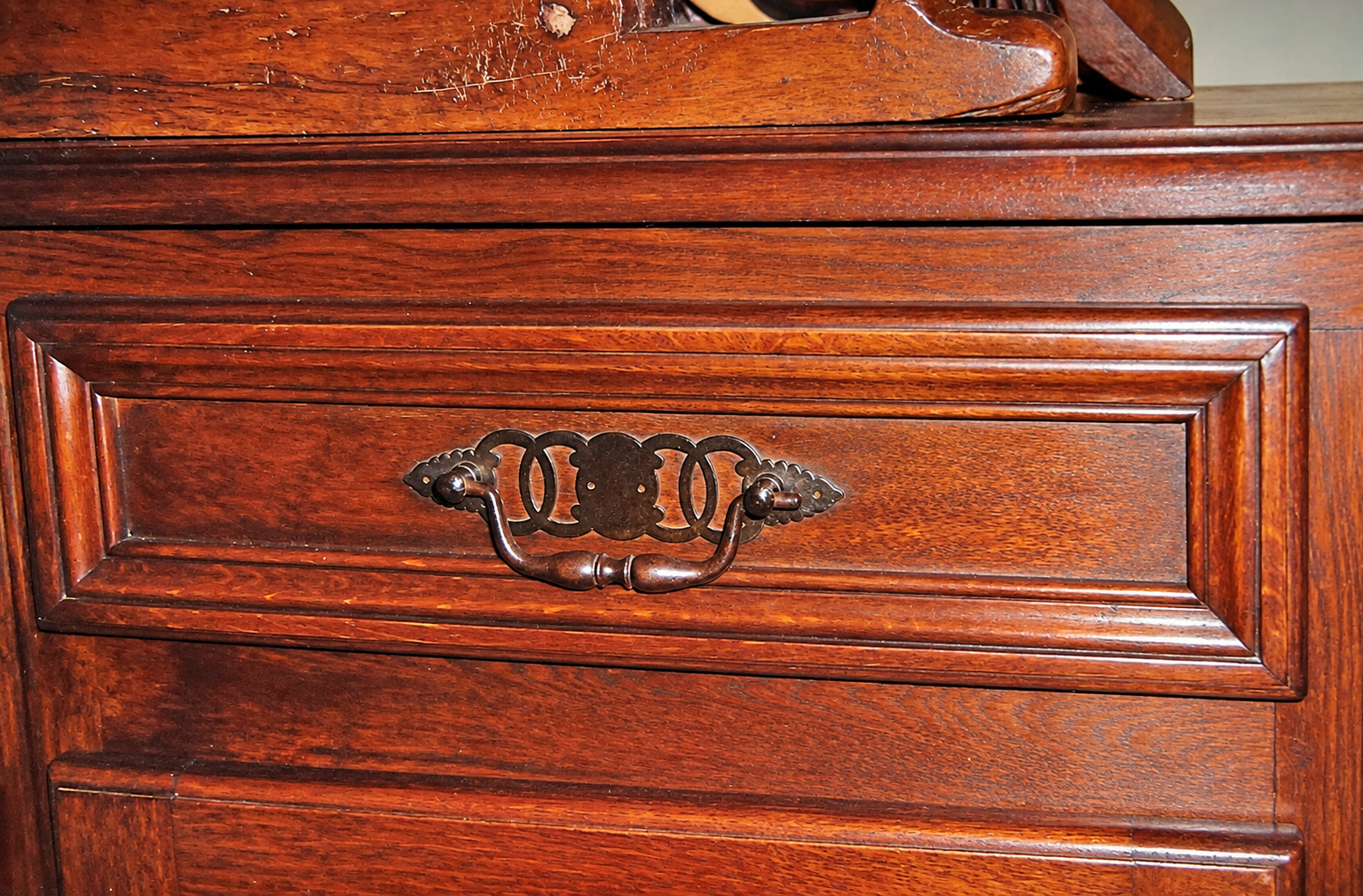A close-up of a kitchen drawer front, its molding and decorative pull.
