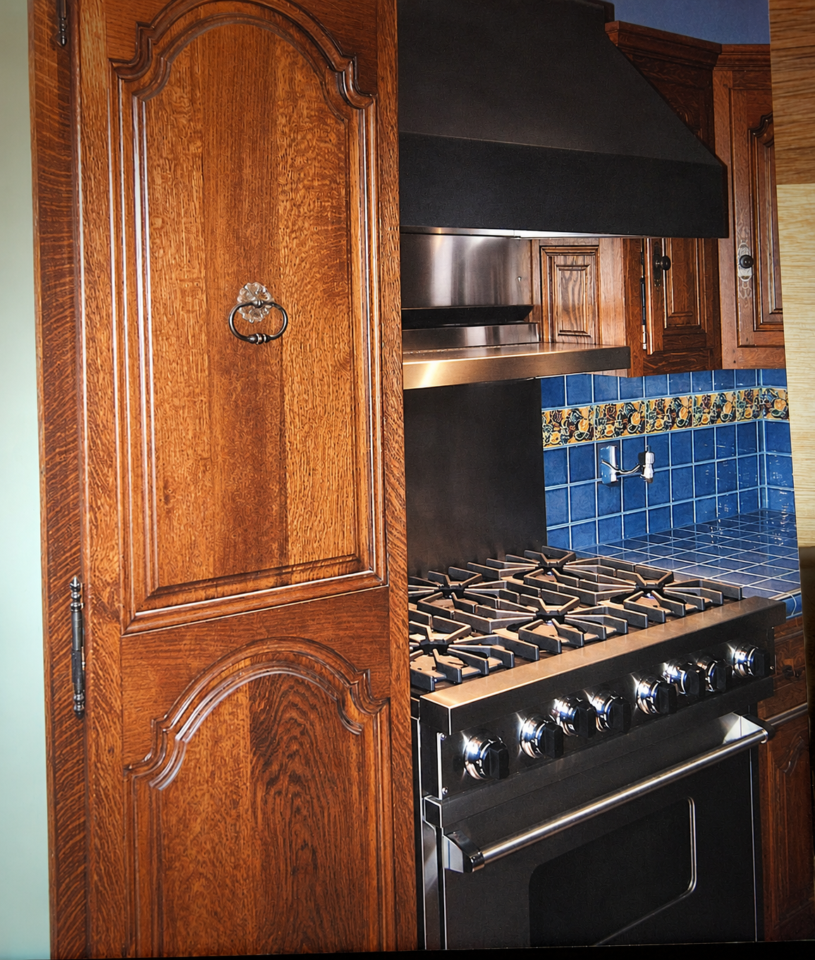 Custom cabinetry beside the range shows the antique-inspired door profiles.